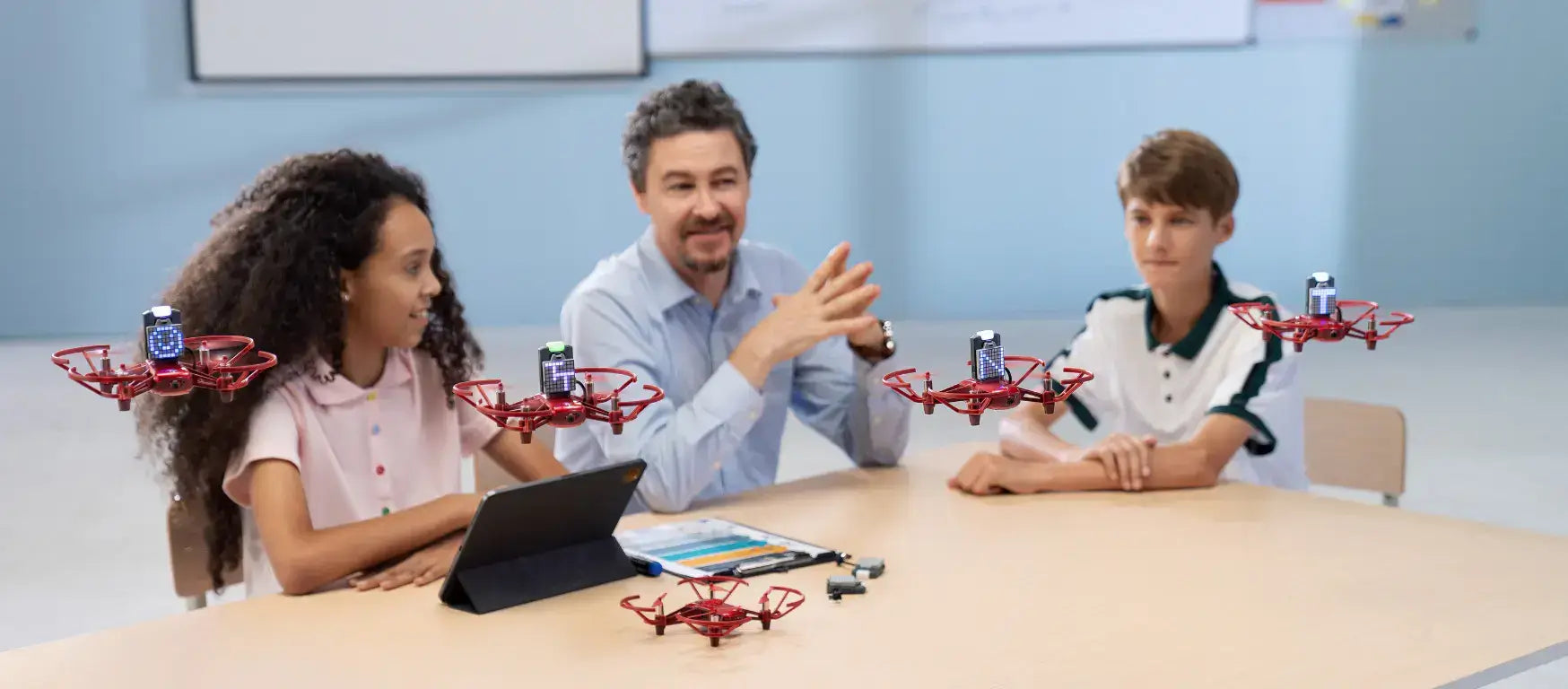 Teacher engaging students with drones in a classroom, promoting interactive STEM learning.