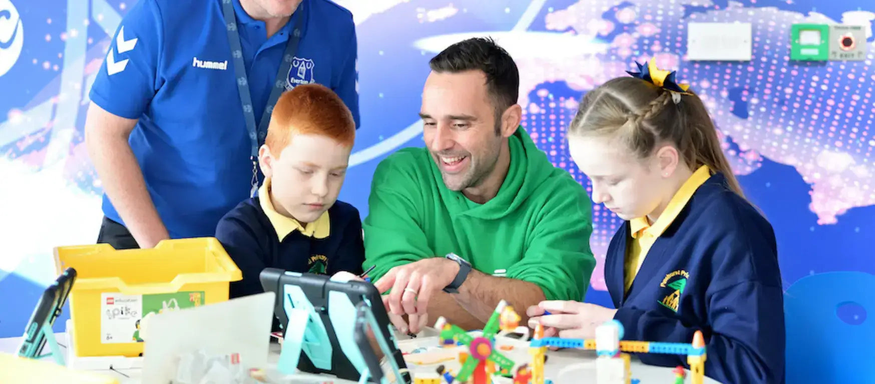 Children and mentor engaging in digital skills activities at Everton In The Community's lab in Merseyside.