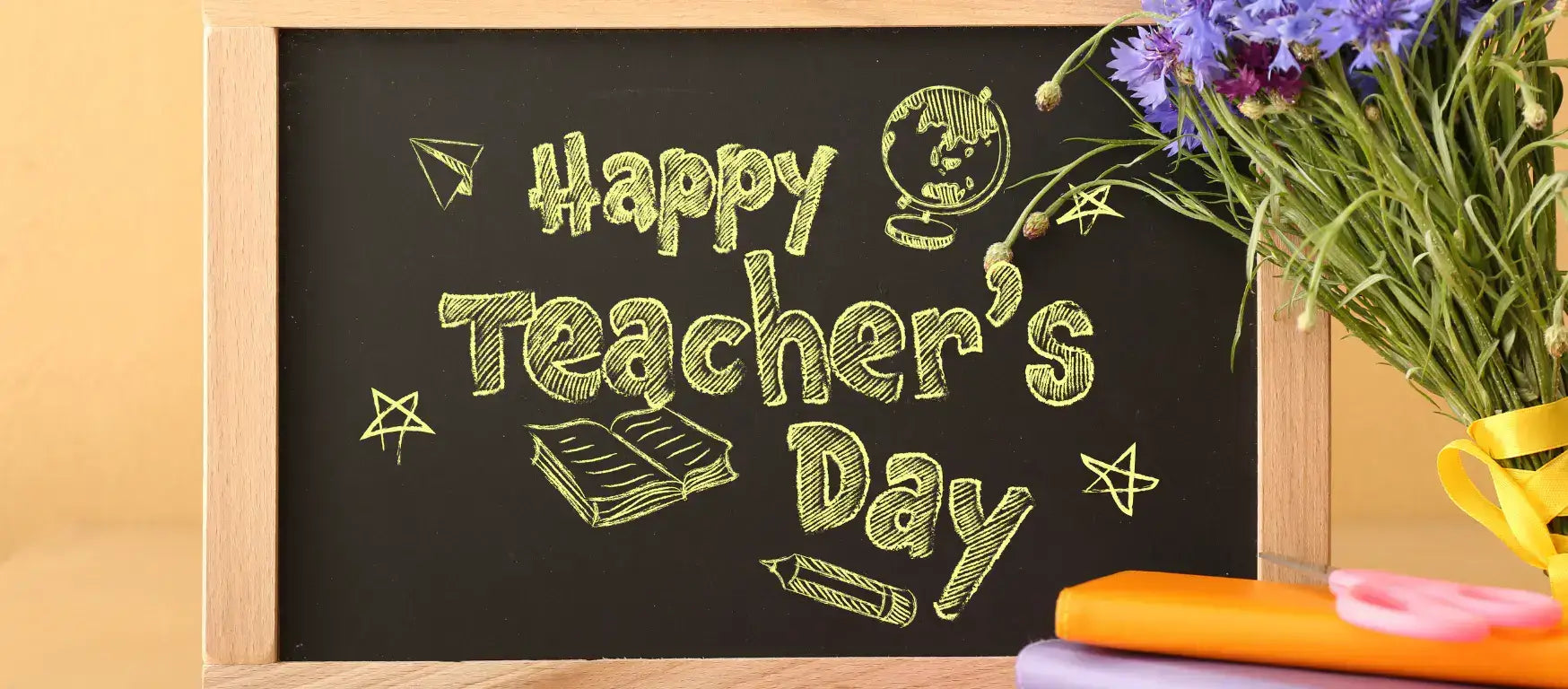 Chalkboard with 'Happy Teacher's Day' written in chalk, surrounded by colorful stationery and flowers.