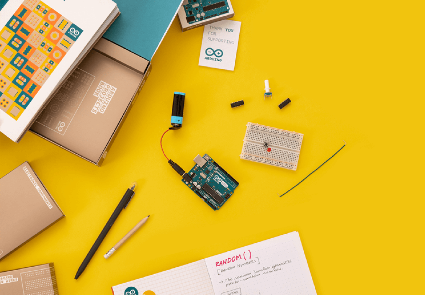 Flat lay of Arduino project with breadboard, components, and project box against a vibrant yellow background.
