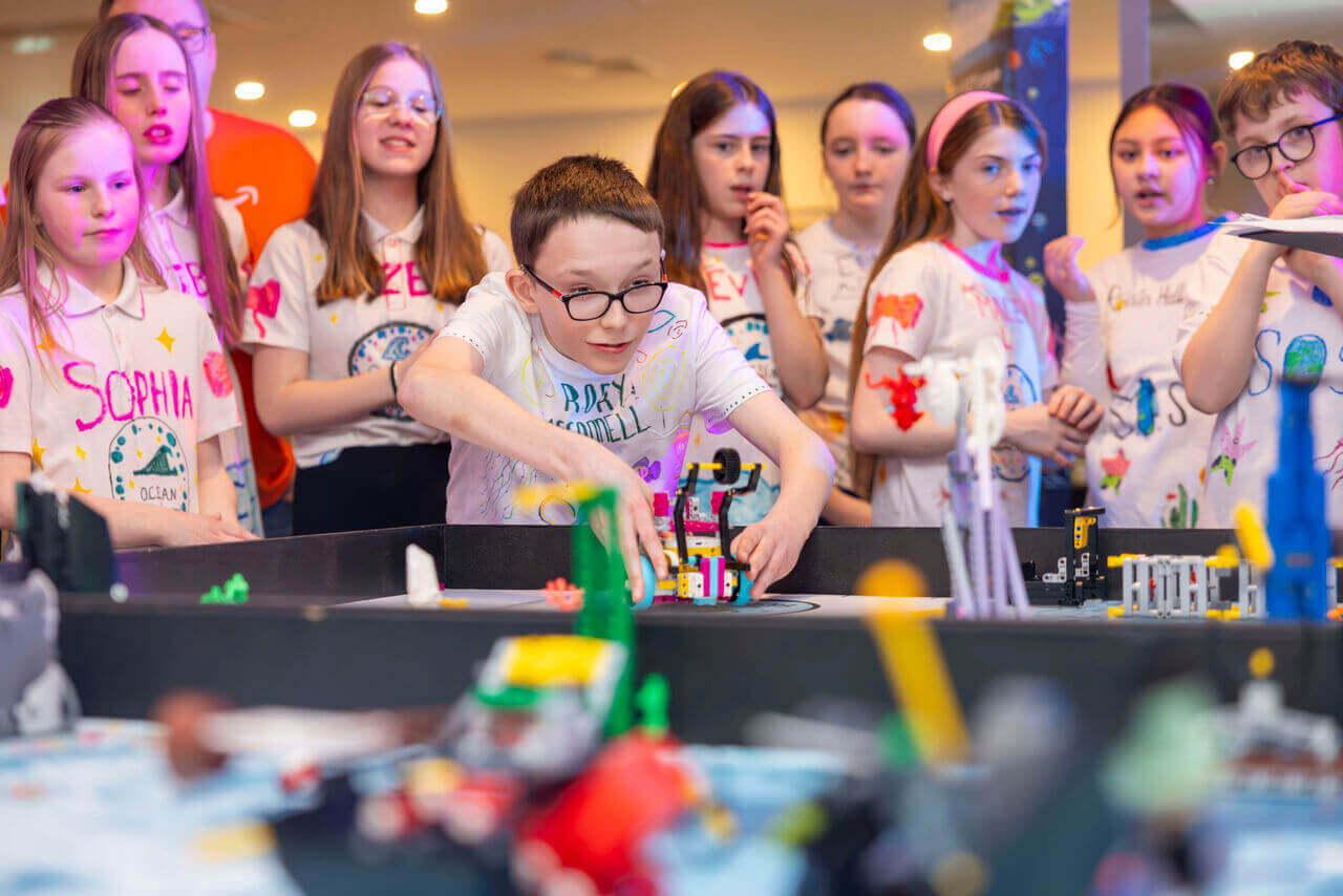 Children engaged in a robotics activity, building with Lego at a STEM event.