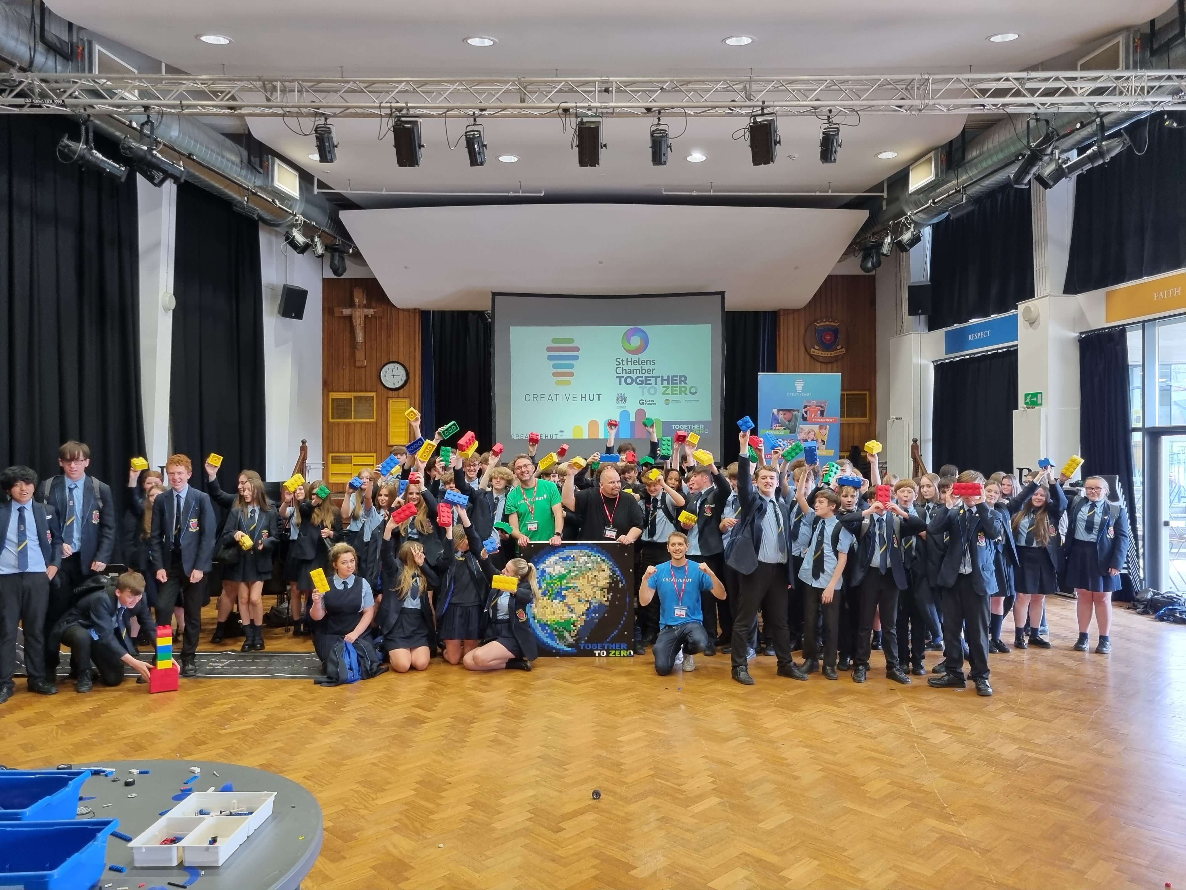 Group of students celebrating on stage with colorful props and banners promoting togetherness and community.