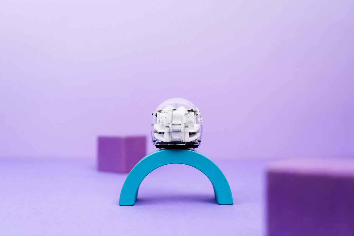 A small white space helmet sitting on a teal arch, with purple blocks in a softly lit, colorful background.