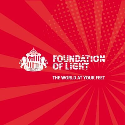 Foundation of Light logo with red background and text 'THE WORLD AT YOUR FEET', symbolizing community support and engagement.