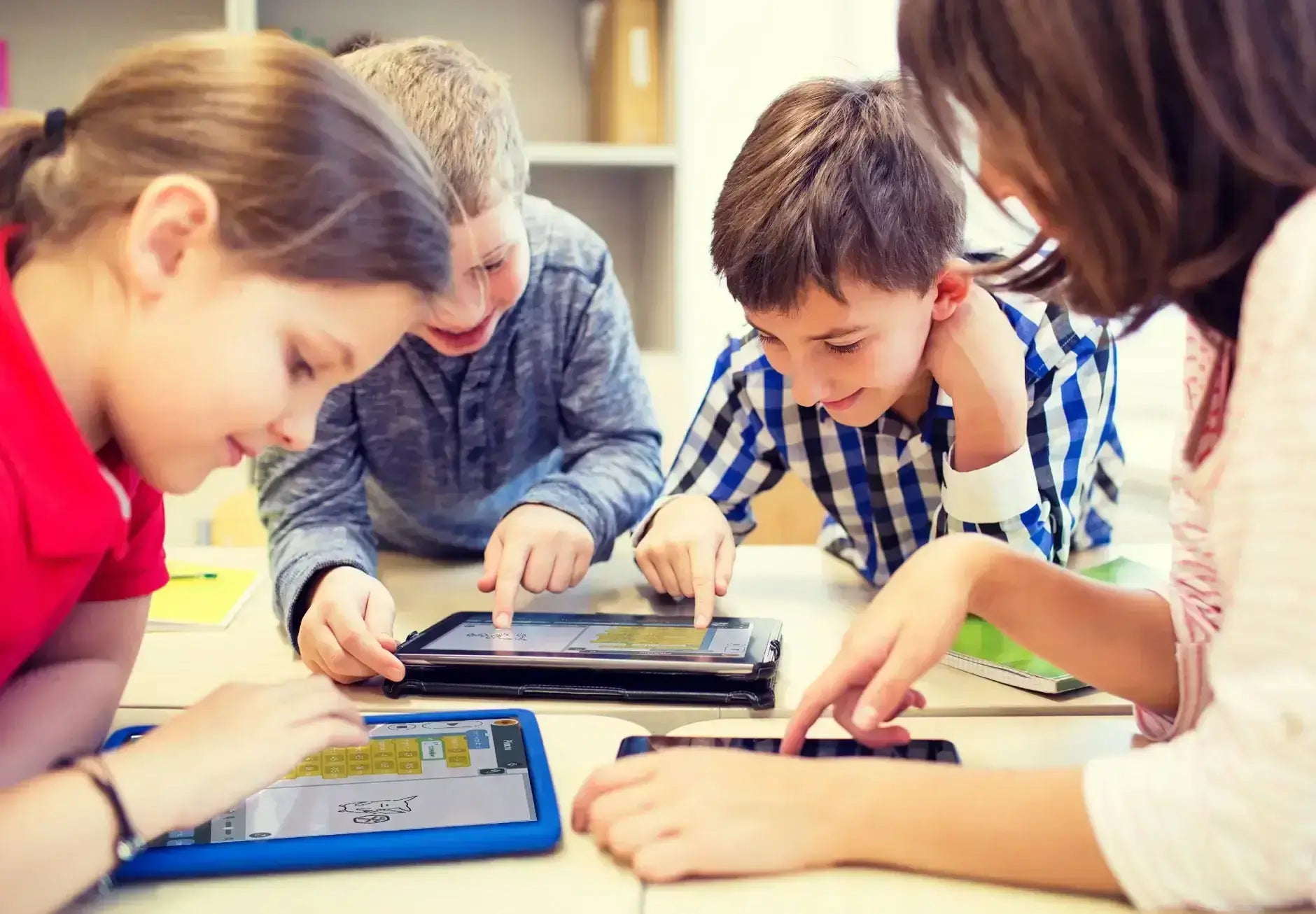 Group of children actively engaging with tablets, exploring apps, and collaborating in a classroom setting.