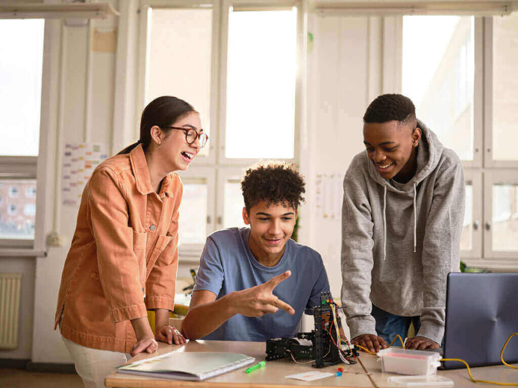 Group of diverse students collaborating on a robotics project in a bright classroom setting.