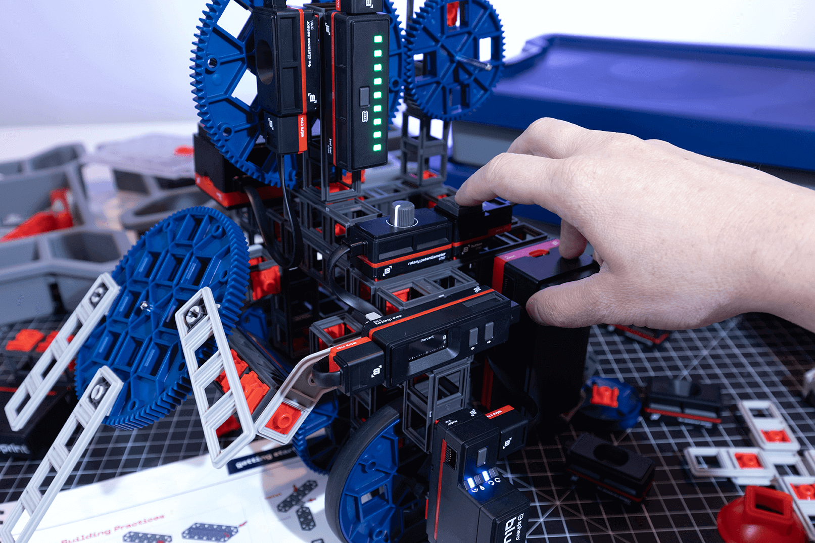 A hand adjusting components of a colorful mechanical model, showcasing creativity and engineering design.