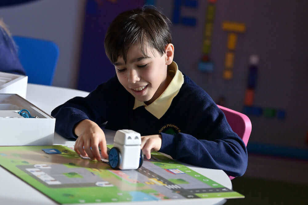A young boy enjoys playing with a toy car on a colorful learning mat, promoting hands-on education.