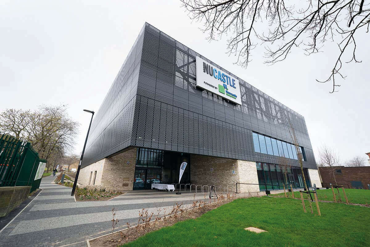 Modern Newcastle building with a green logo and landscaped pathway in front.