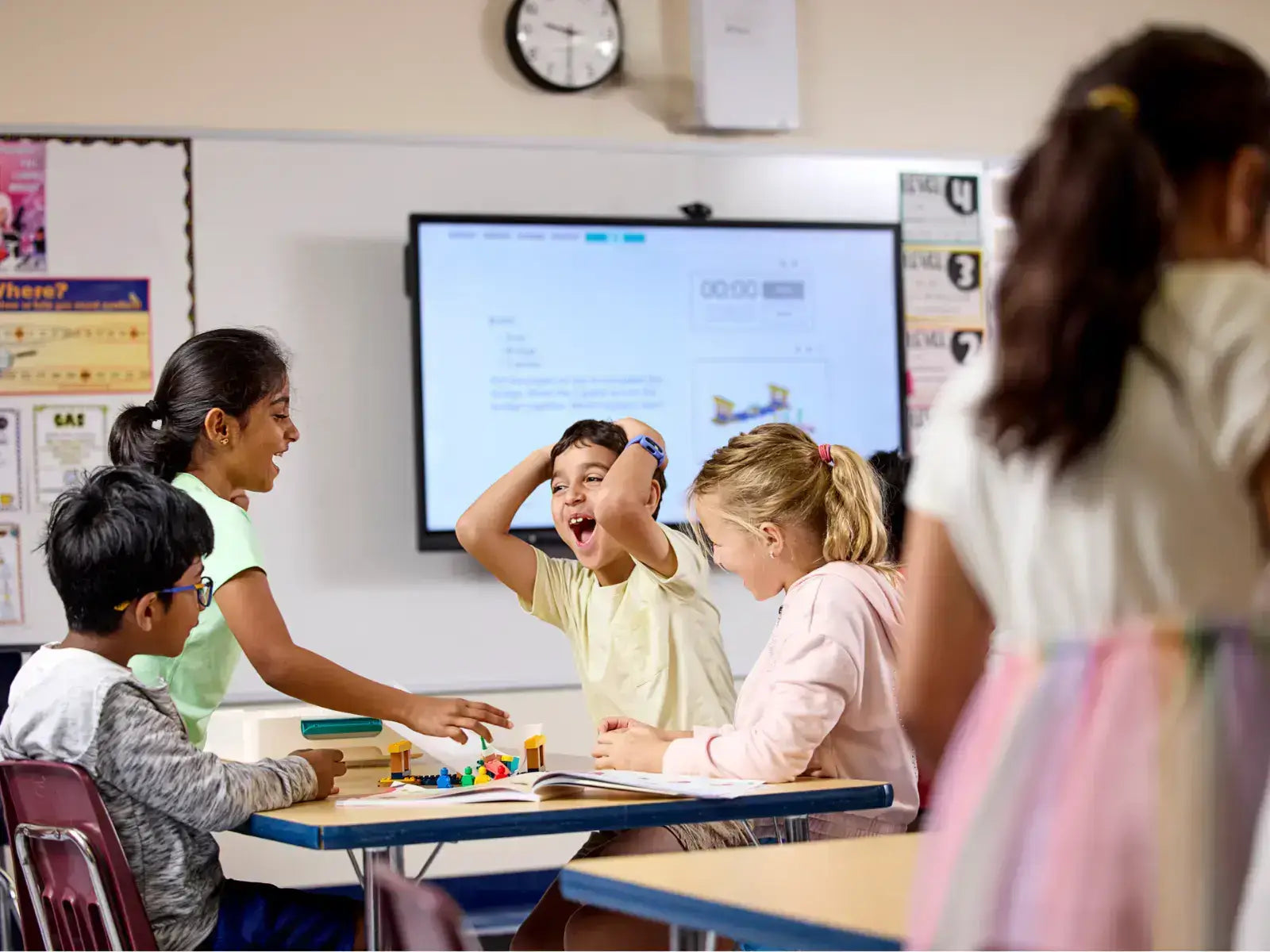 Students joyfully engaging in hands-on learning activities in a classroom with educational technology.