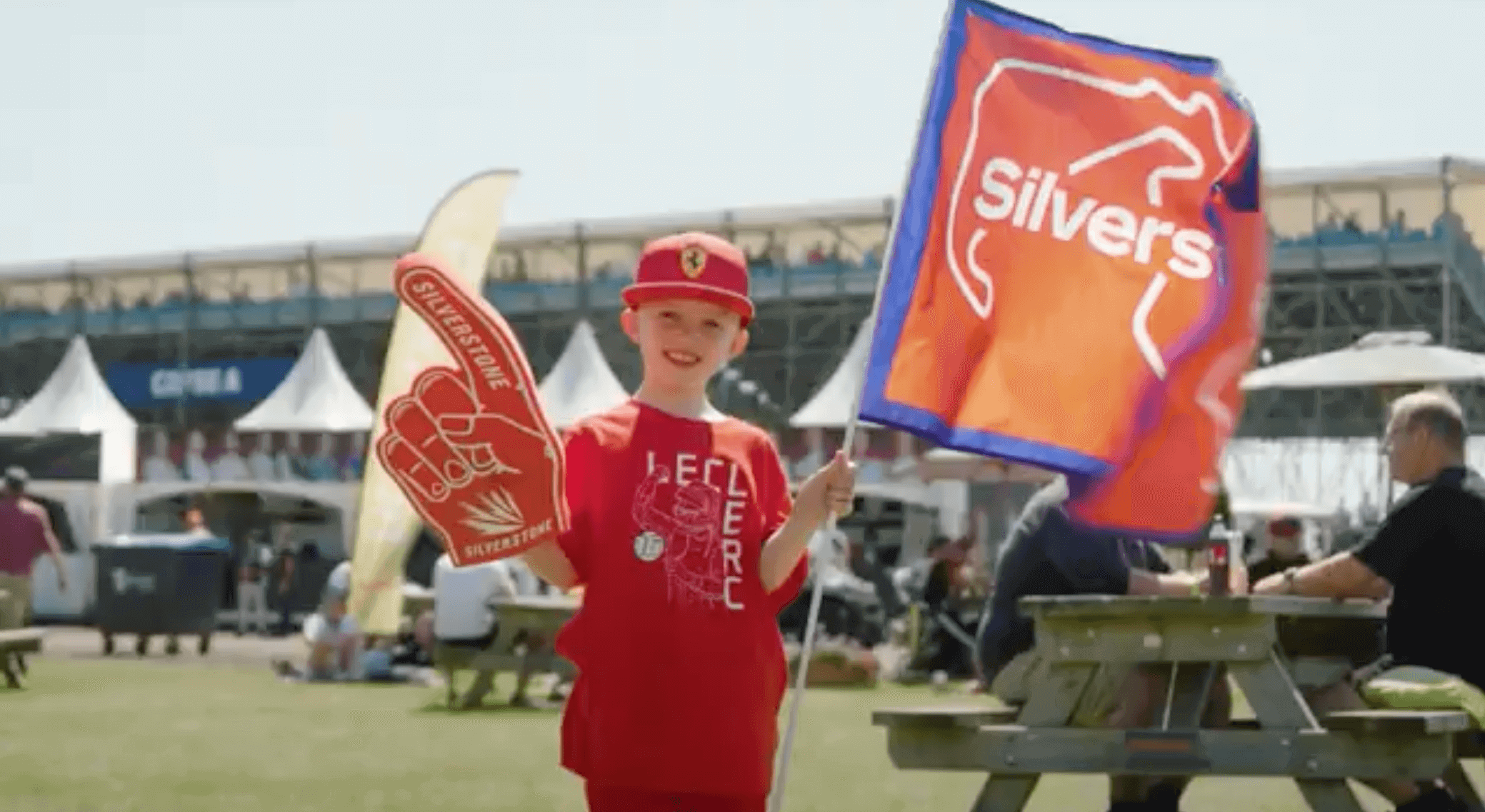 Young fan in red shirt with foam finger and flag at a lively outdoor event, showing team spirit and excitement.