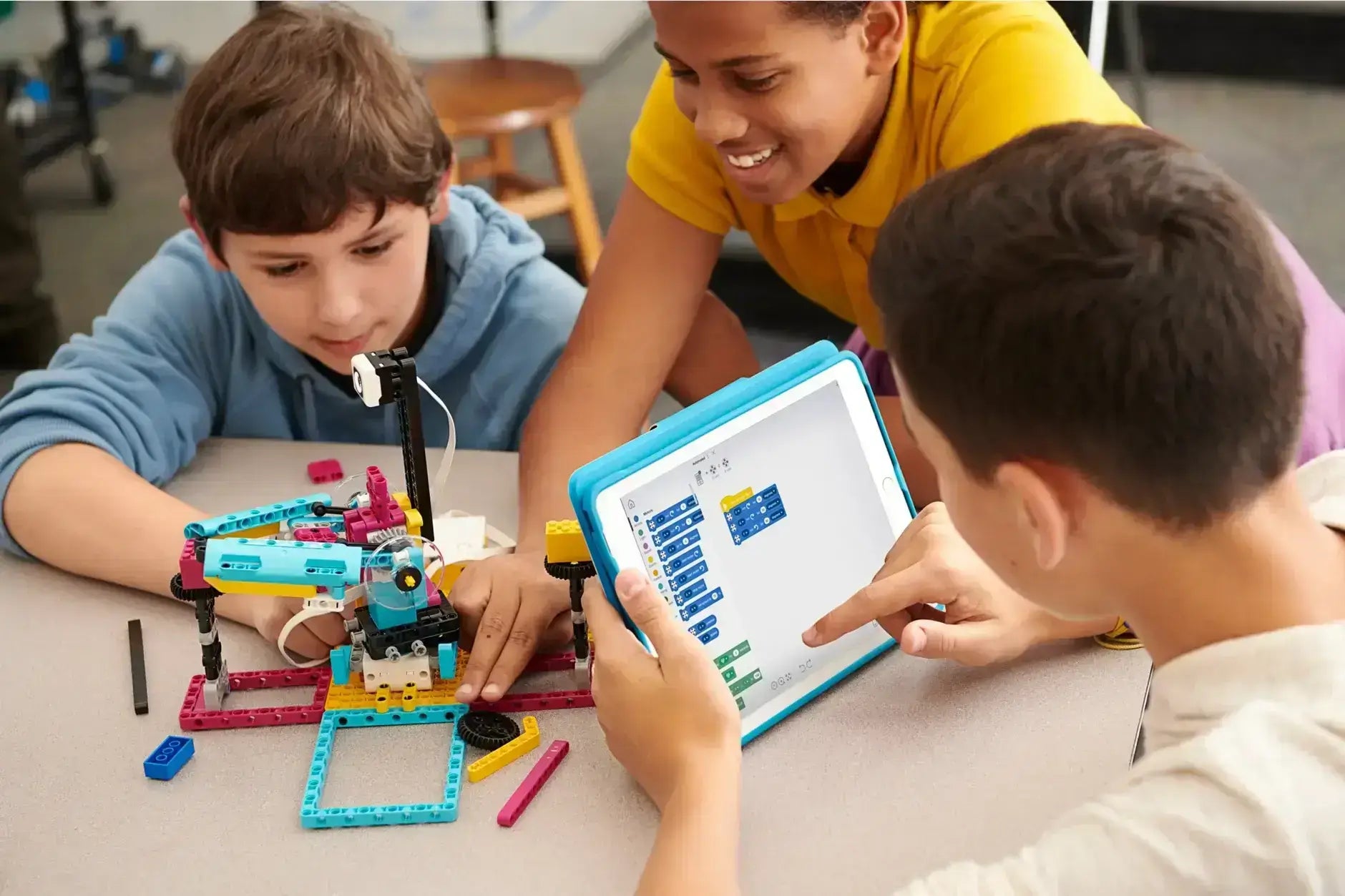 Children engaged in robotics and coding with a tablet, demonstrating teamwork and creativity.