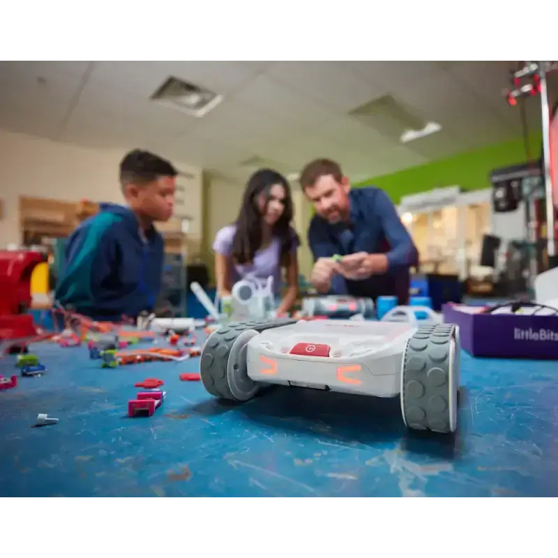 Children and instructor working with a robot in a creative STEM classroom setting.