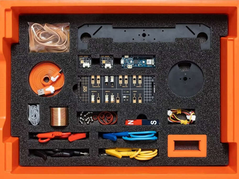 Top view of an electronics kit with various components organized in a foam insert inside an orange case.