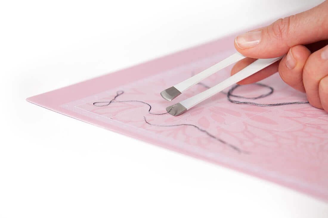 Cricut Applicator and Remover Set showing tweezers removing fabric from a Cricut mat.