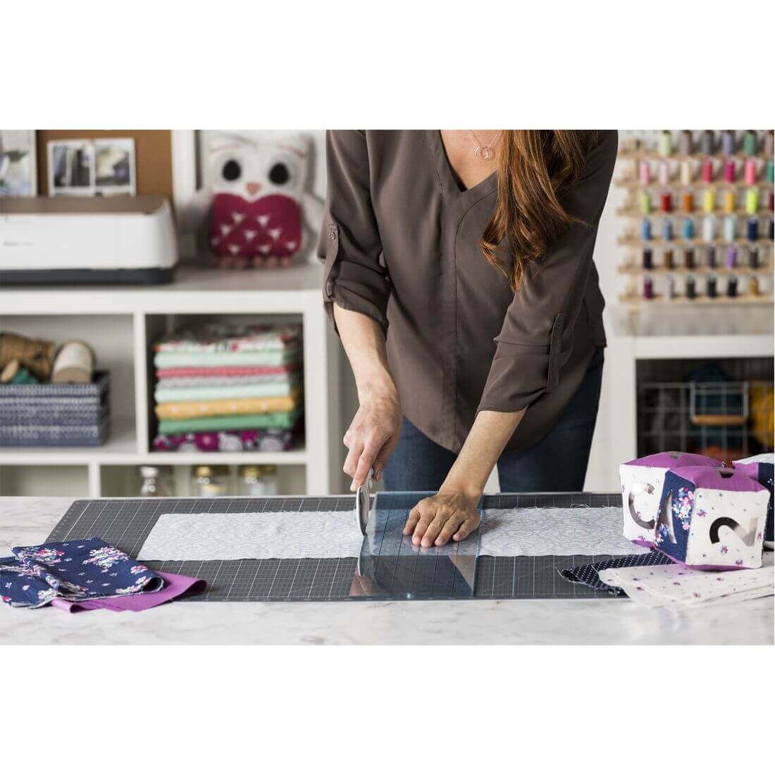 User cutting fabric on a Cricut self-healing cutting mat, showcasing craftsmanship in a creative workspace.