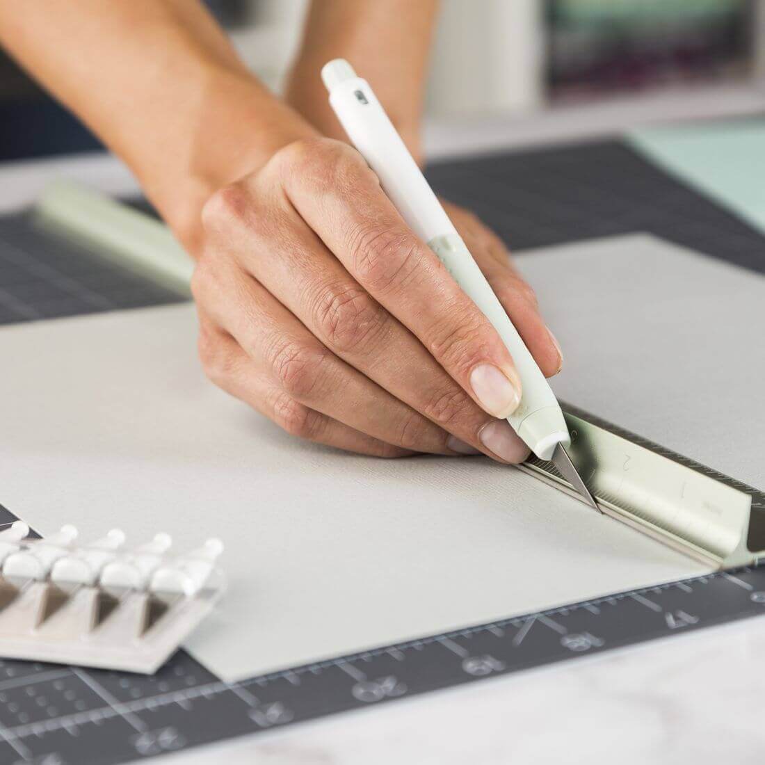 Person using Cricut TrueControl Knife to cut paper on a crafting mat, showcasing precision and control.