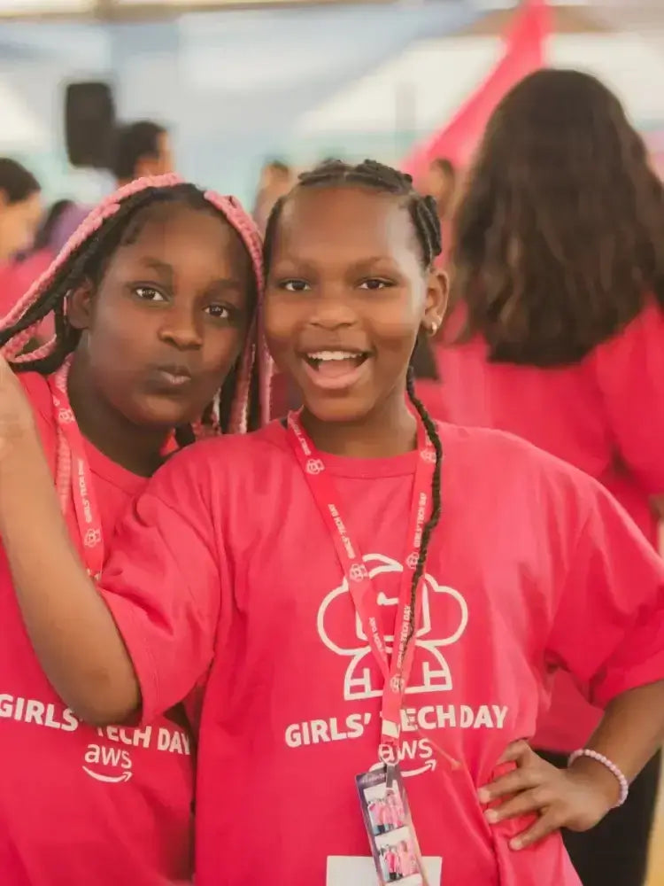 Two smiling girls in pink t-shirts at Girls Tech Day event, promoting STEM and youth empowerment.