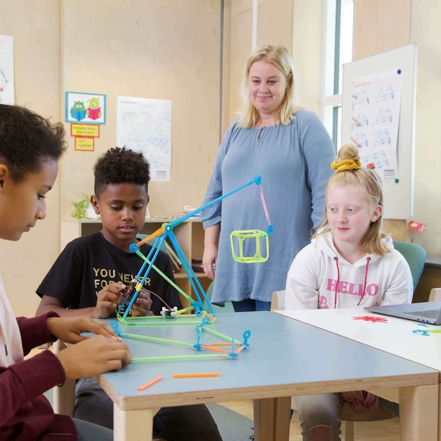 Children building a robotic structure with micro:bit and Strawbees in a classroom setting.