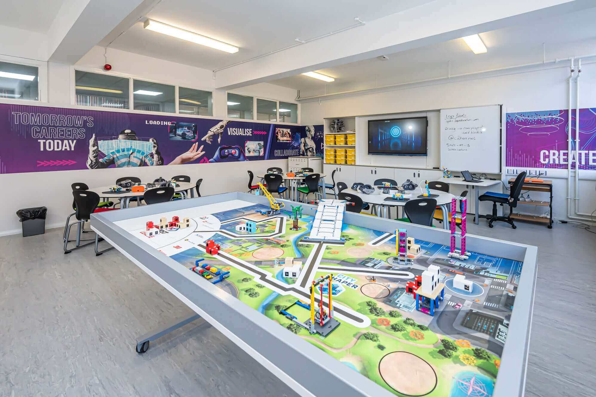 Interactive classroom with a model landscape and technology displays, fostering creative learning and innovation.