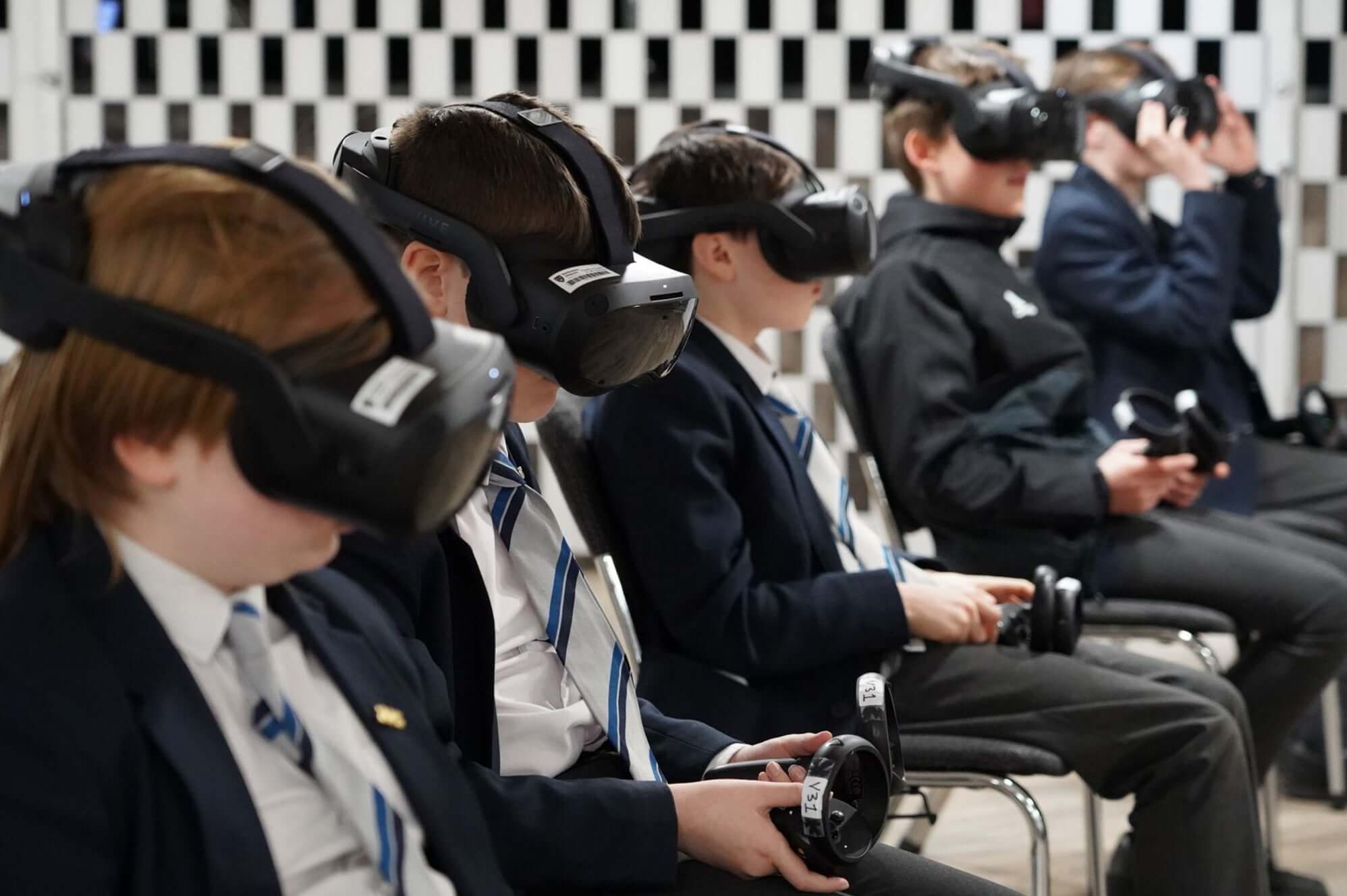 Students wearing virtual reality headsets while sitting in a classroom, engaging with technology.