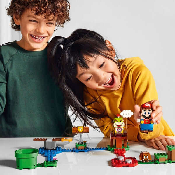 Kids enjoying LEGO Super Mario Adventure set with Mario and Bowser Jr. figures on a tabletop.