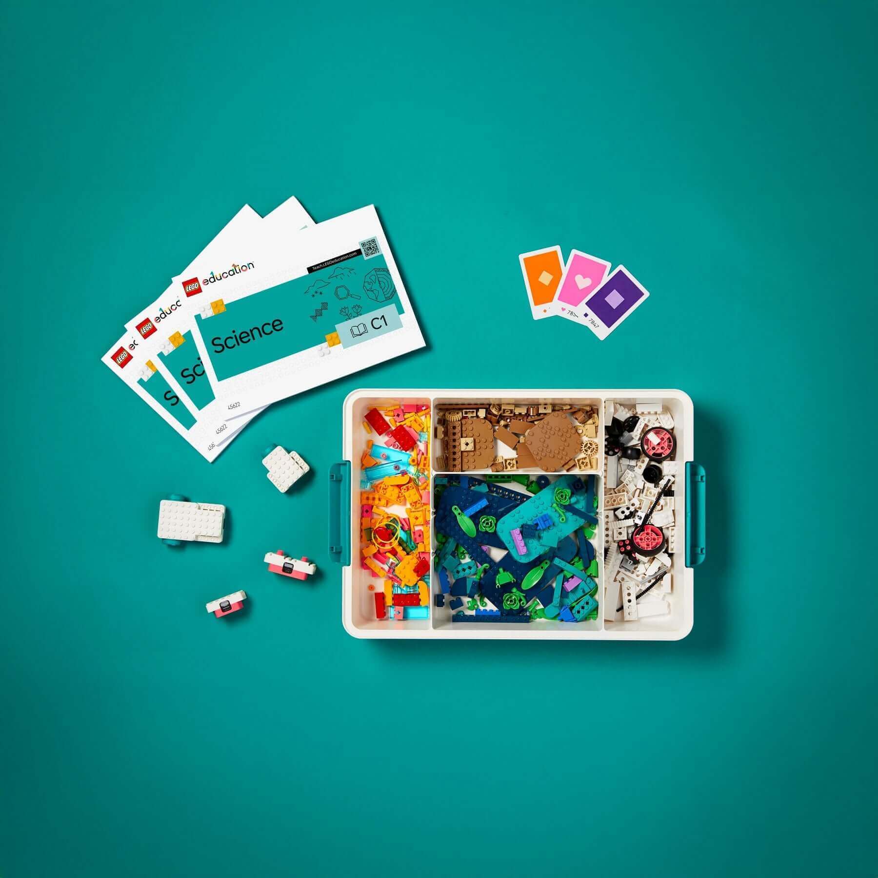 Colorful science education kit with building materials and activity cards on a teal background.