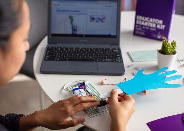 Educator using the littleBits Starter Kit to create a project with a laptop and colorful materials.