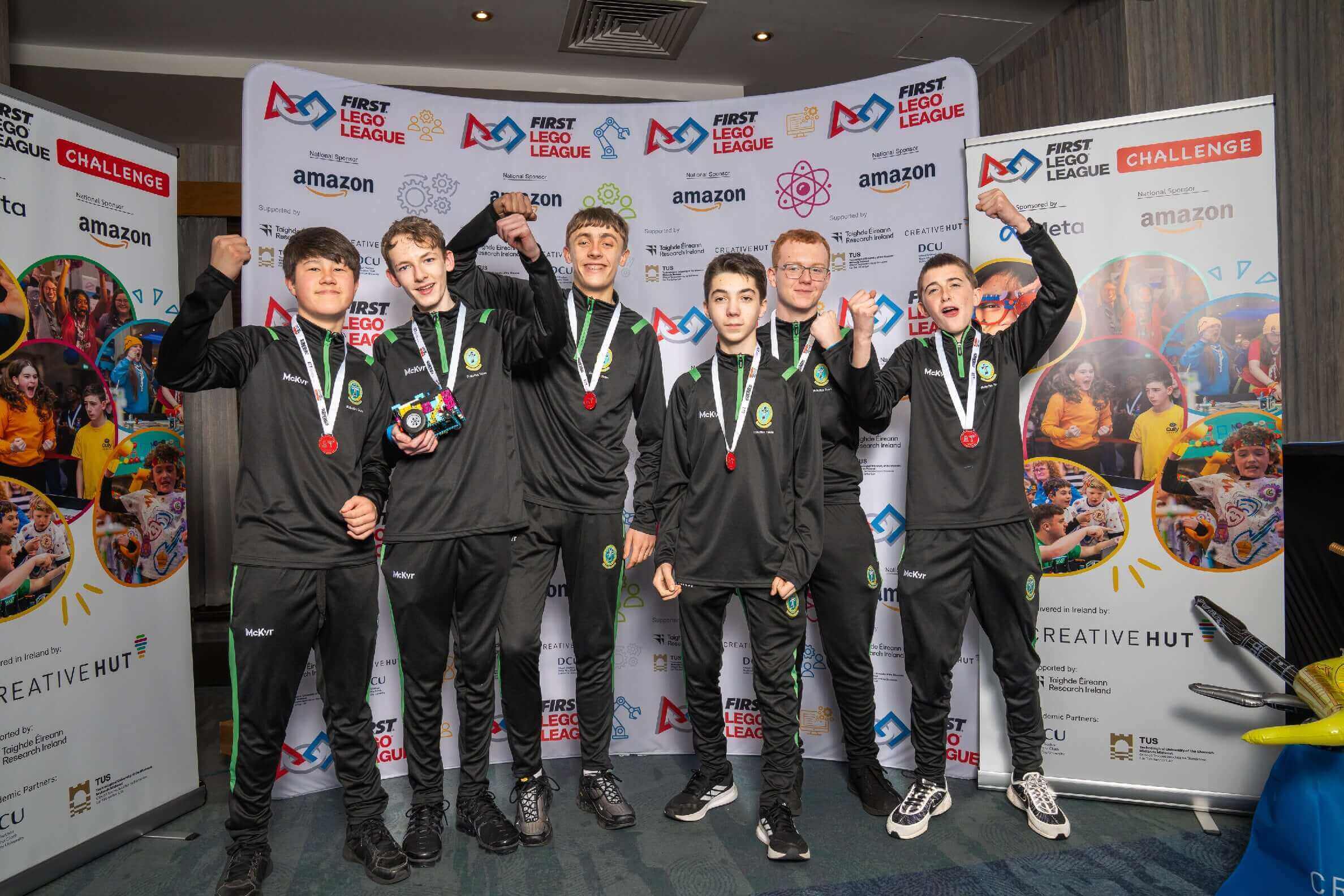 Team of young competitors celebrating with medals at the FIRST LEGO League event, showcasing teamwork and innovation.