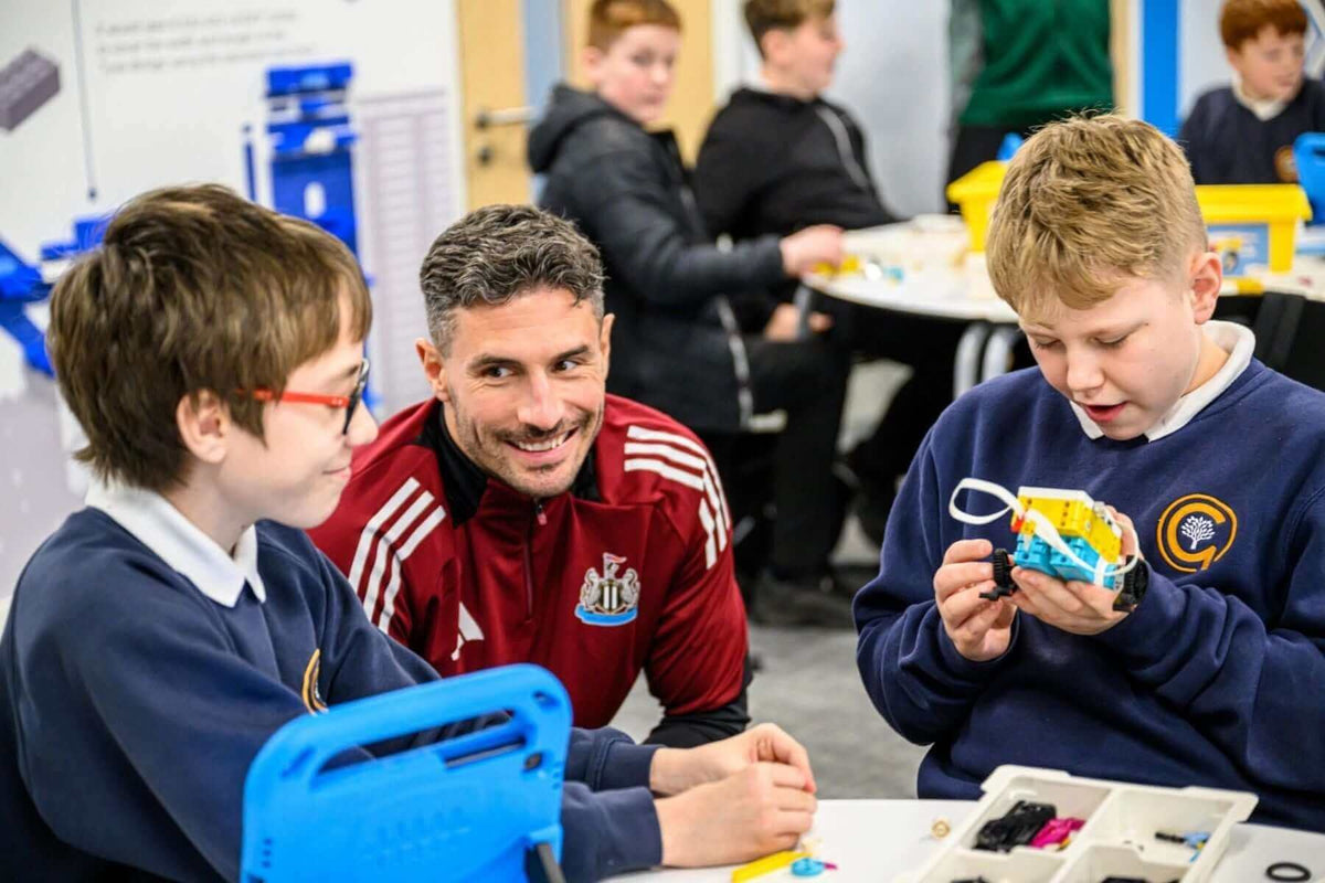 A teacher engaging with students as they build projects in a classroom, showcasing hands-on learning and teamwork.