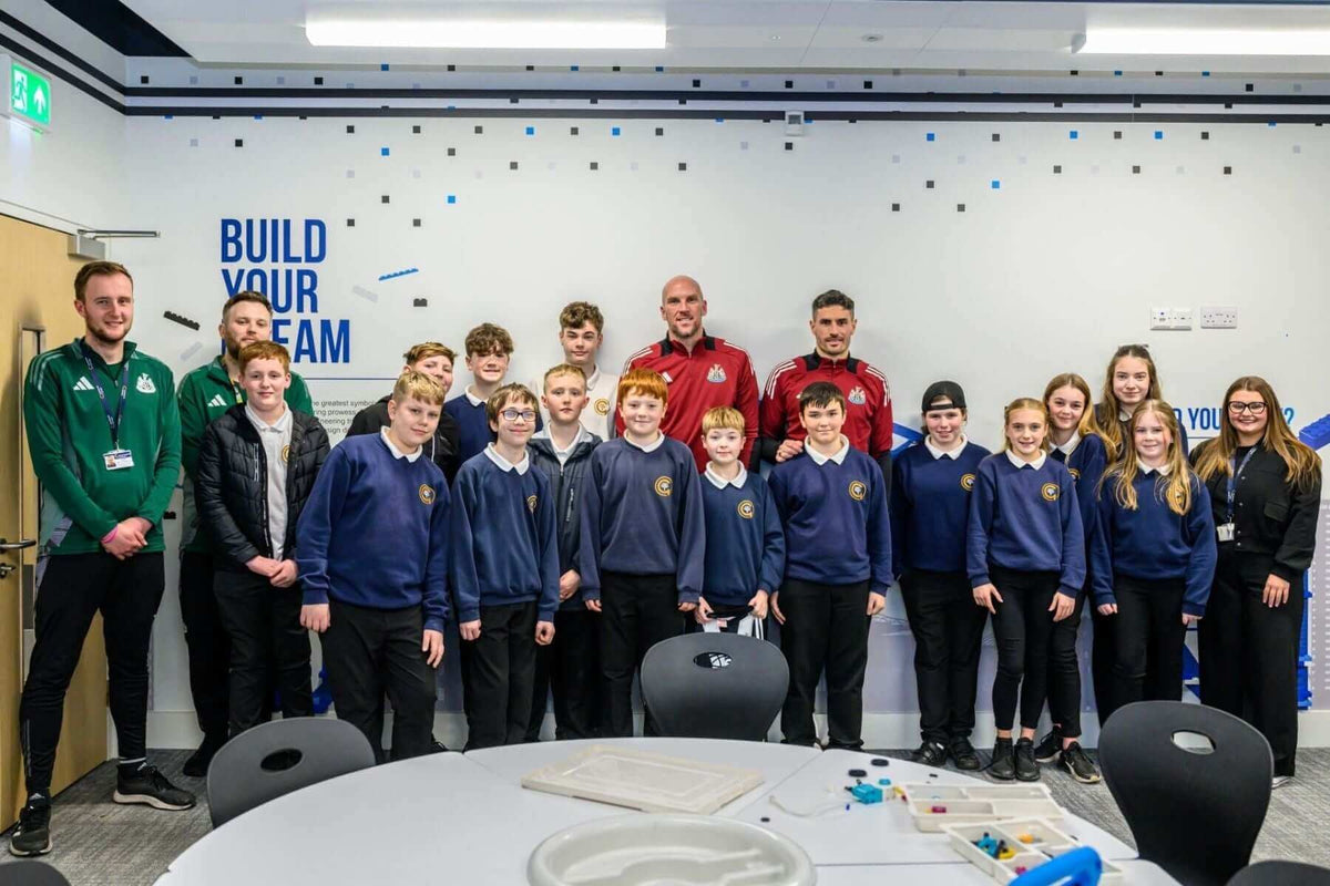 Group photo of students and coaches in a classroom setting, promoting team building and collaboration.