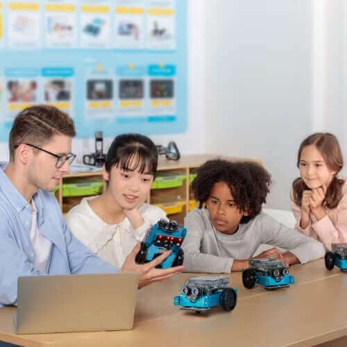 Students and teacher engaging in robotics education, exploring robotic cars in a classroom setting.