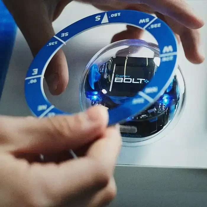 Person adjusting the orientation of a Sphero BOLT robot using a numbered ring for programming.