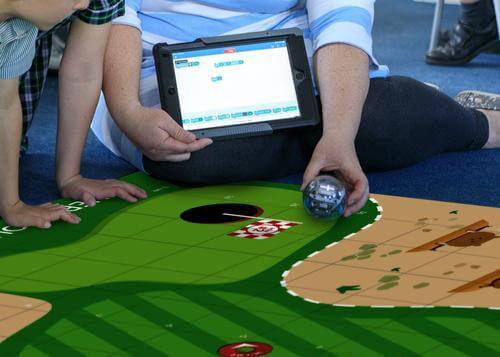 Child and adult using Sphero Code Mat with tablet to control coding challenges and games.