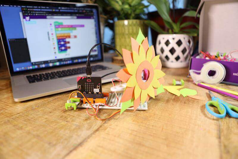 Sphero Craft Kit displayed with a colorful flower creation and a laptop programming interface nearby.