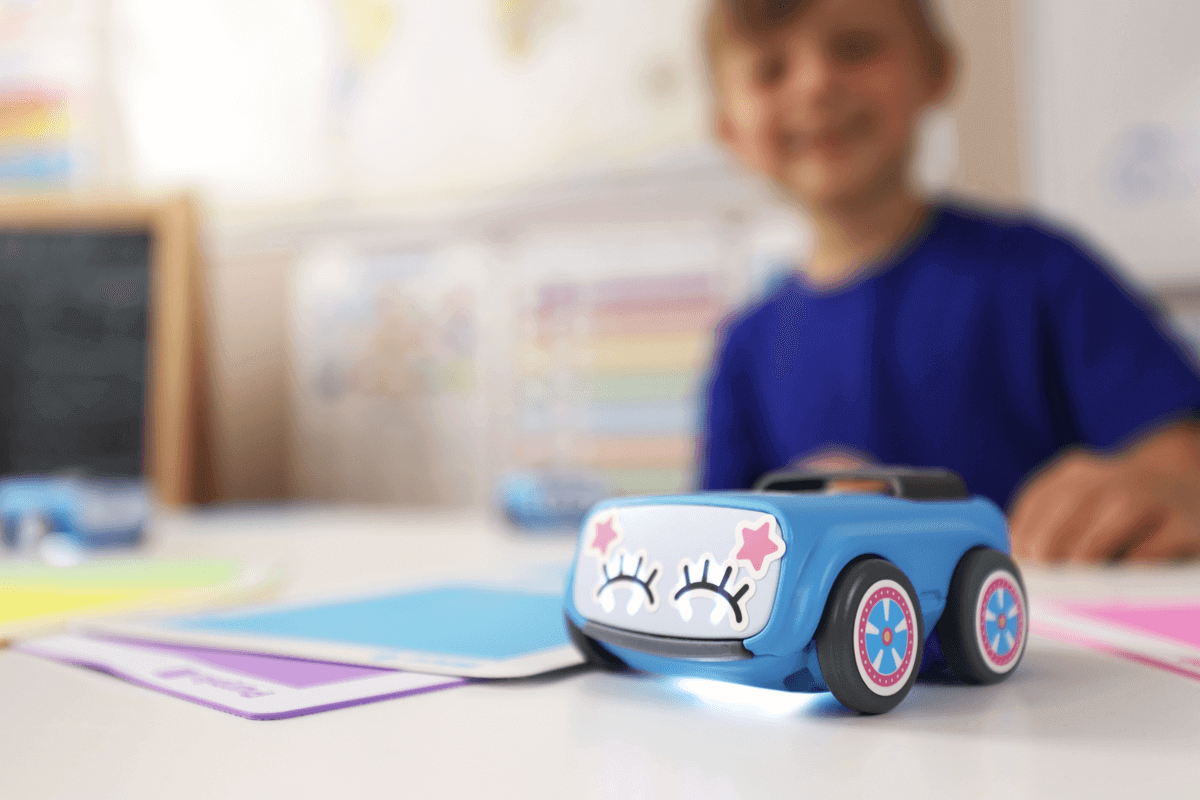 Child playing with Sphero indi robot on a classroom table surrounded by colorful learning materials.