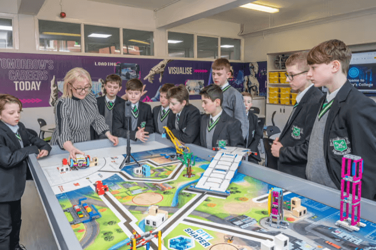 Teacher demonstrating career-focused activities on a model layout to attentive students in a classroom.