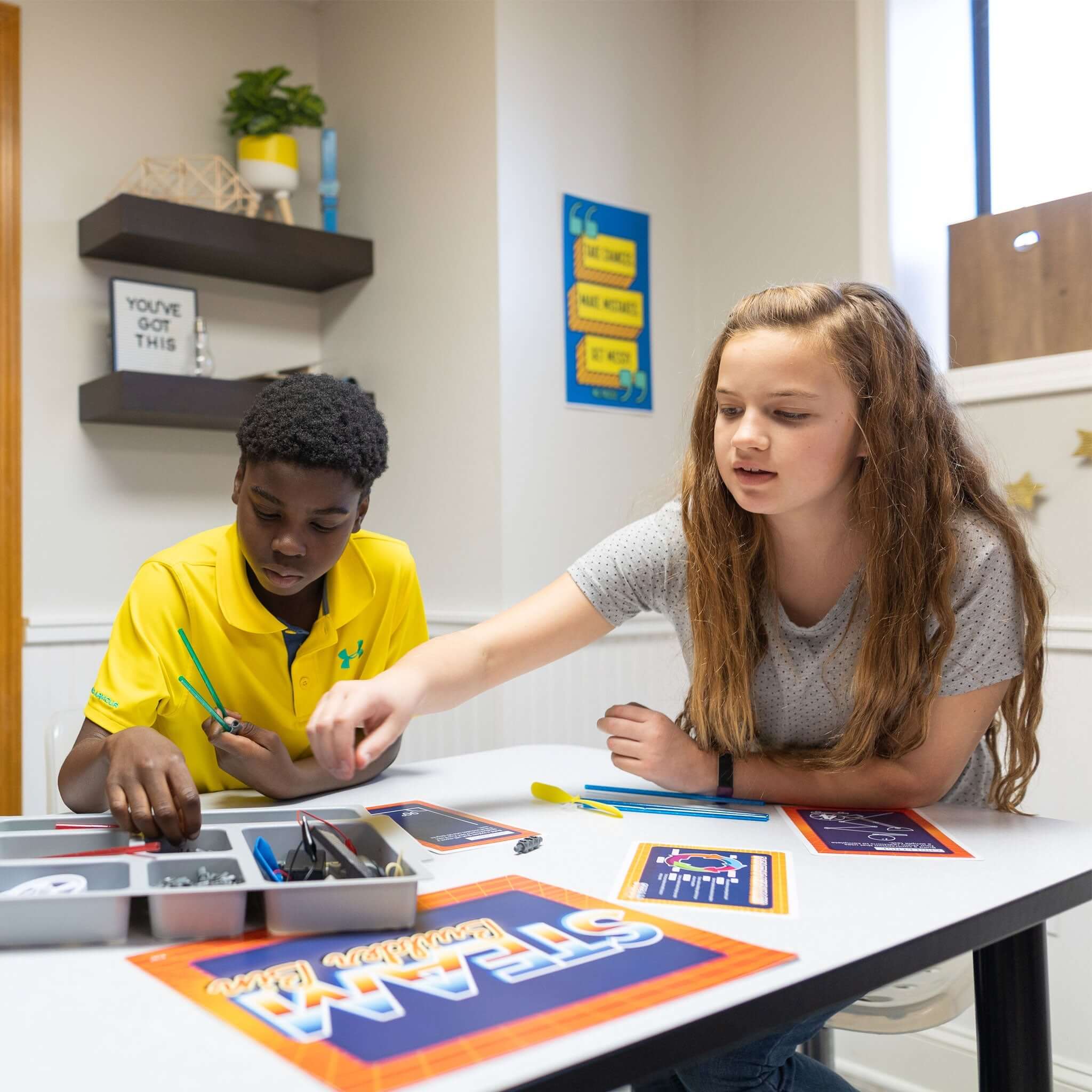 Two students engaging in STEAM activities at a table, exploring creativity and engineering with hands-on materials.