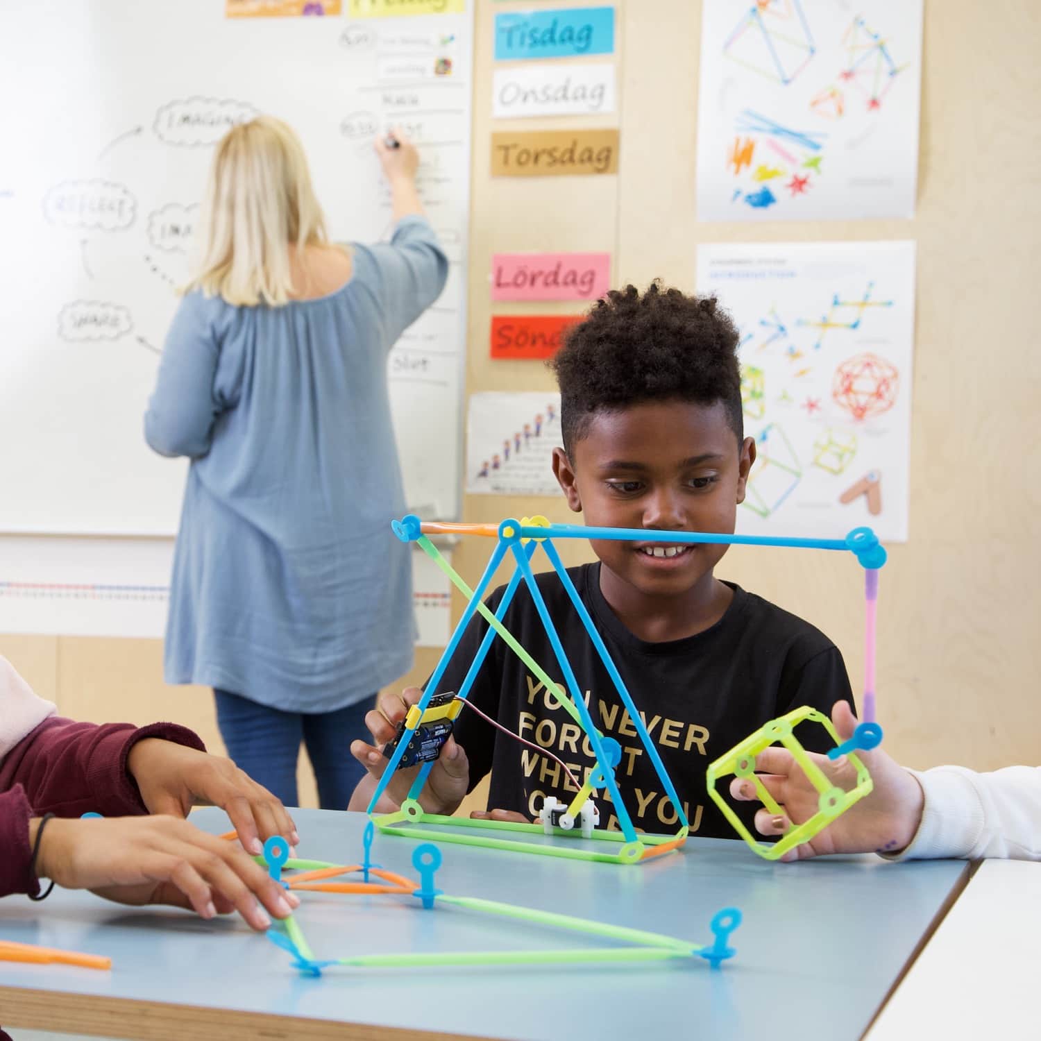 Children using the STEAM School Kit for micro:bit, building structures with colorful straws and connectors in a classroom.