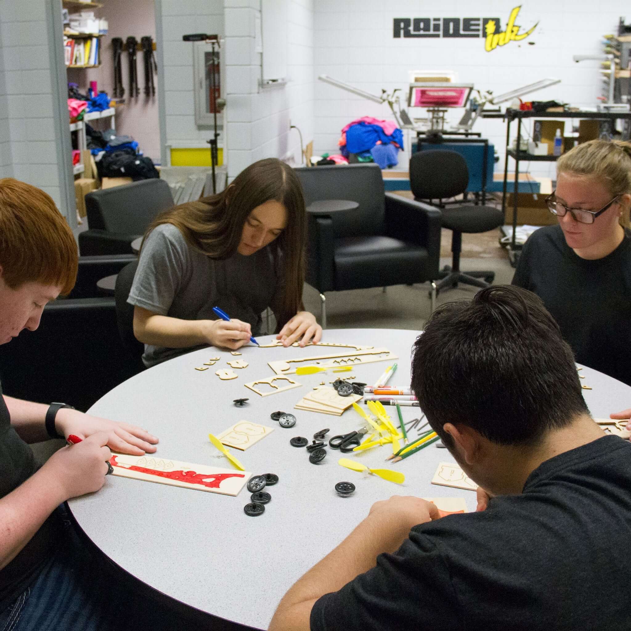 Students assembling the Prop Race Pack at a table, focusing on laser-cut parts and tools for building a racer.