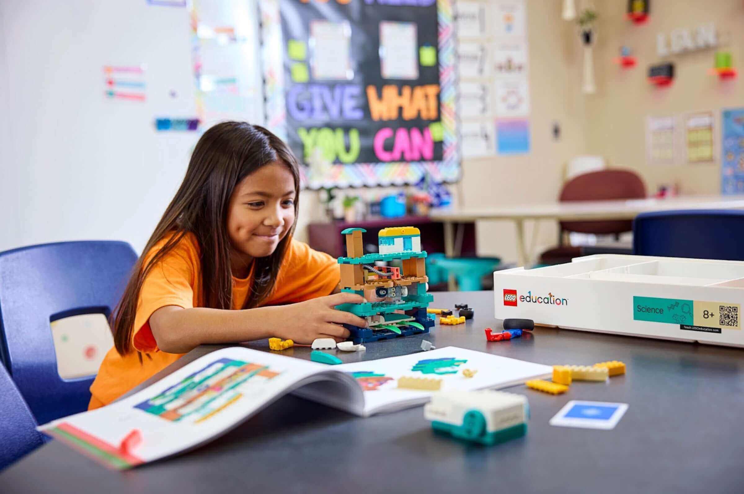 Girl building a robot with colorful blocks in a classroom, promoting STEM learning and creativity.