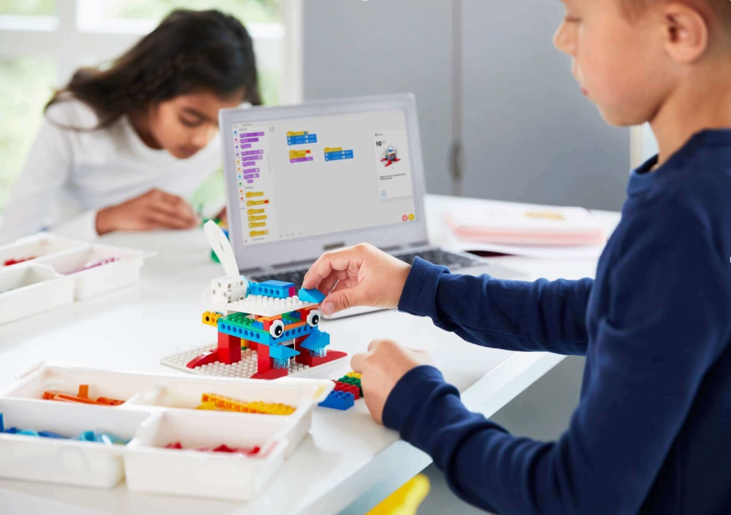 Children engaged in creative coding and building with LEGO at a workstation, promoting STEM learning.