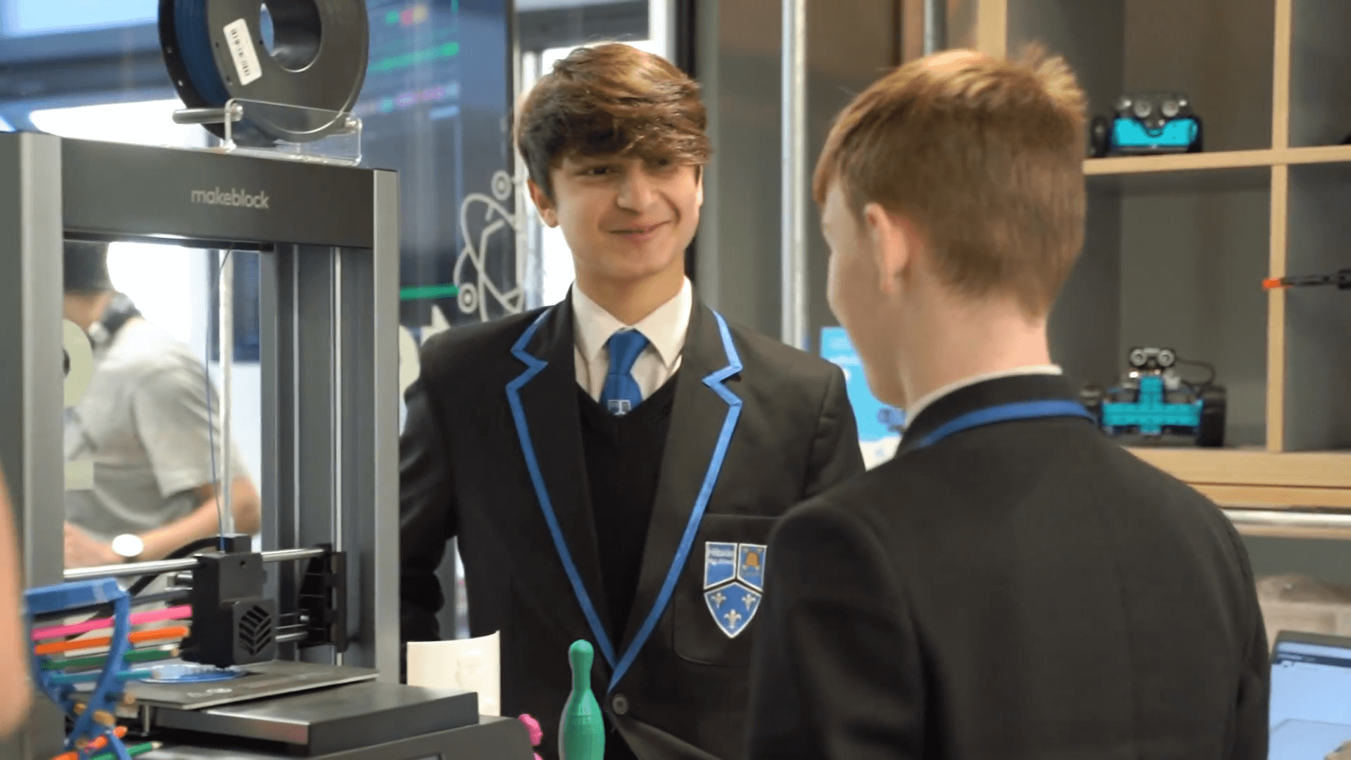 Students engaged in a discussion about 3D printing in a school setting, showcasing innovation and technology.