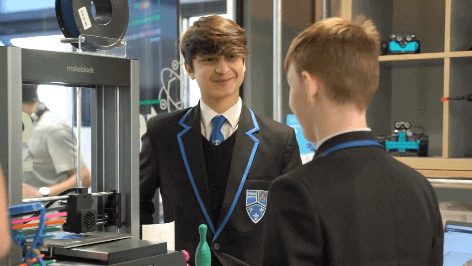 Students engaged in a discussion about 3D printing in a school setting, showcasing innovation and technology.