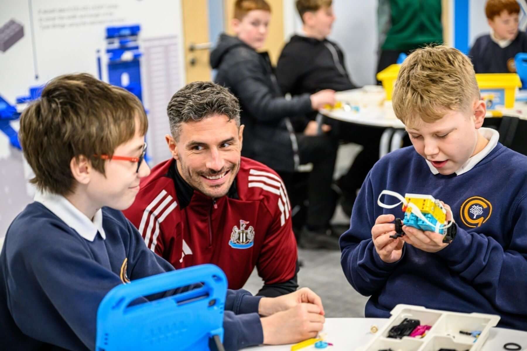 Children engaging in STEM activities with a mentor at Newcastle United Foundation, showcasing teamwork and learning.