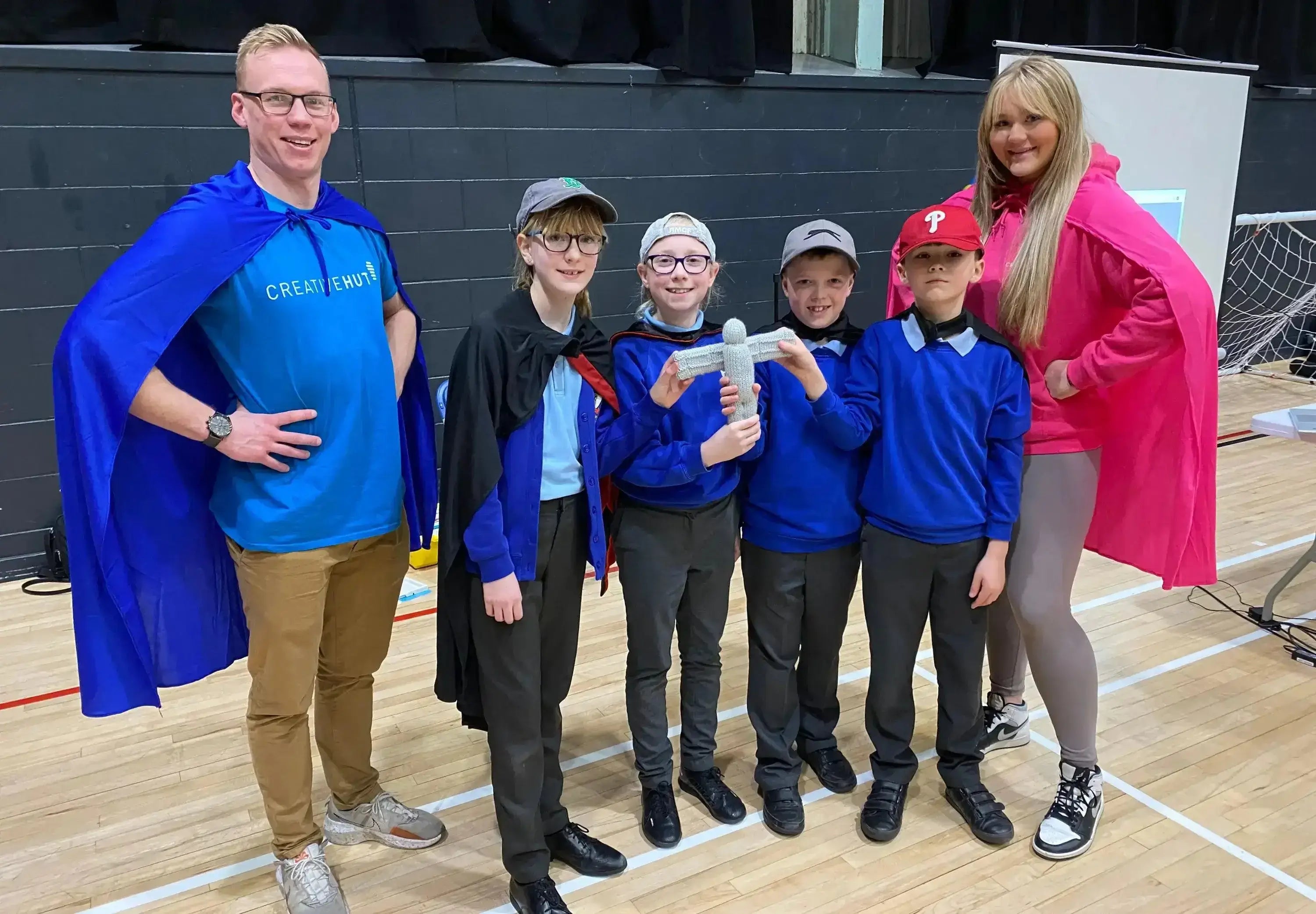 Team of young participants in capes celebrating at FIRST® LEGO® League regionals event, showcasing their teamwork and innovation.
