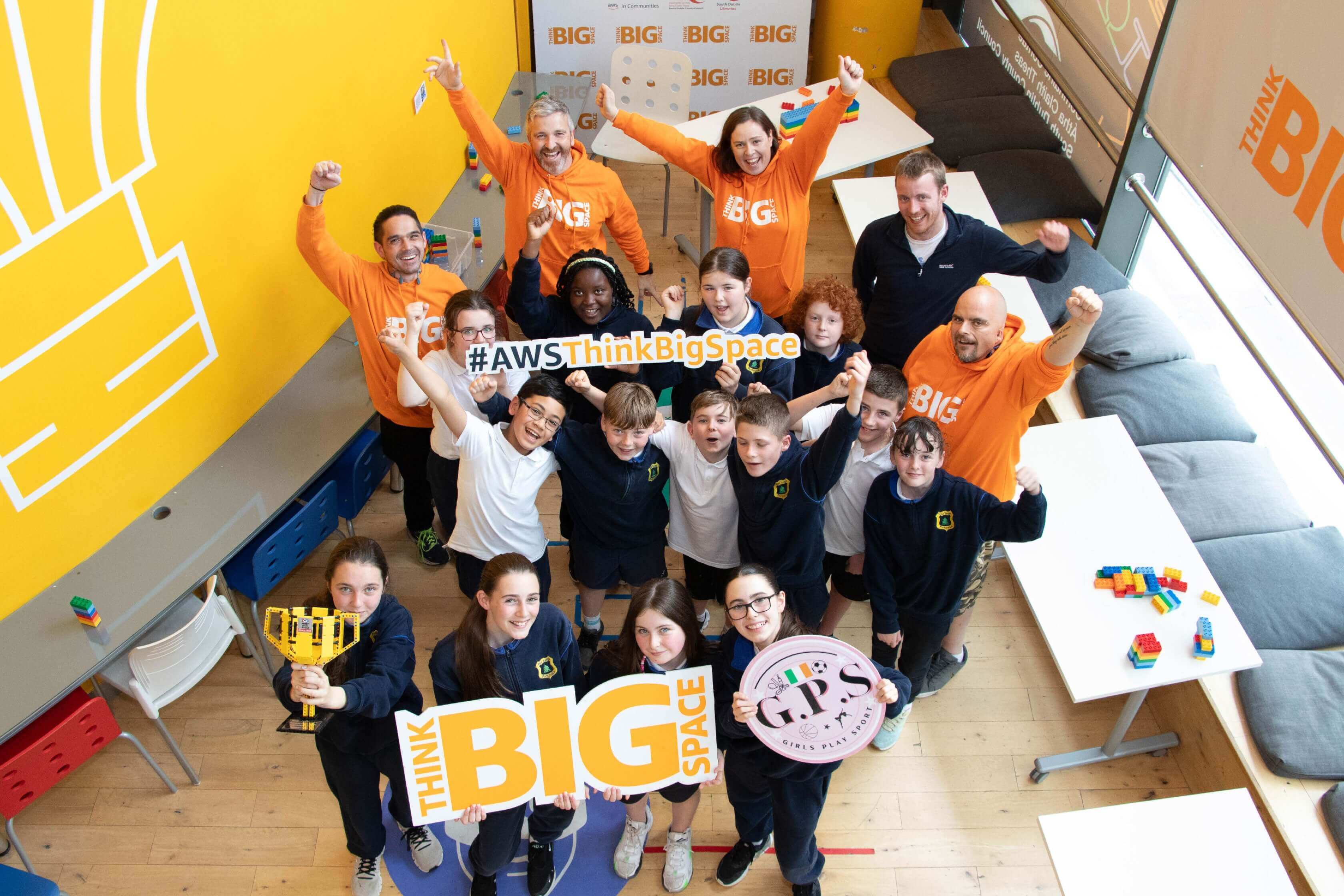 Participants in AWS Think Big event celebrating STEAM education with joyful expressions and banners.