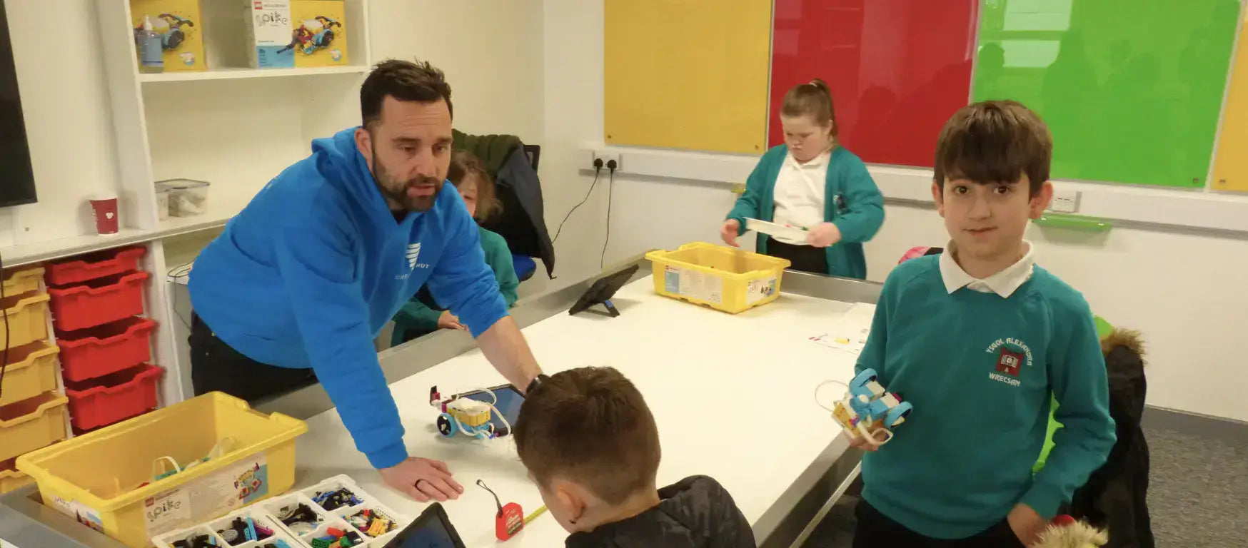 Children engaging in hands-on learning activities at the STEAM Lab in Wrexham with a teacher guiding them.