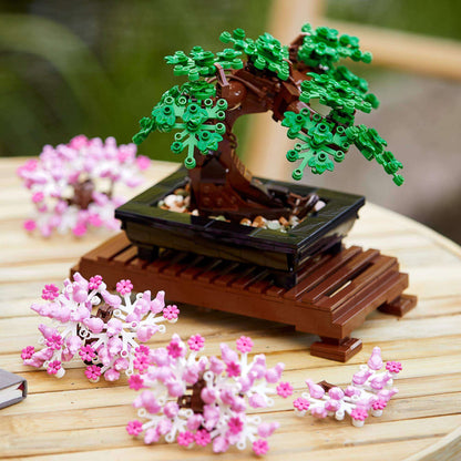 LEGO® Bonsai Tree Building Set 10281 with green leaves and pink cherry blossoms on a wooden stand.