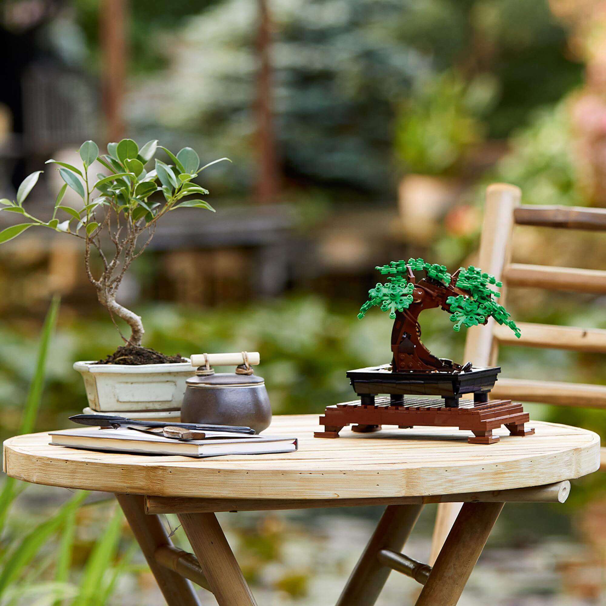 LEGO® Bonsai Tree model with green leaves and pink blossoms on a garden table, showcasing a creative hobby project.